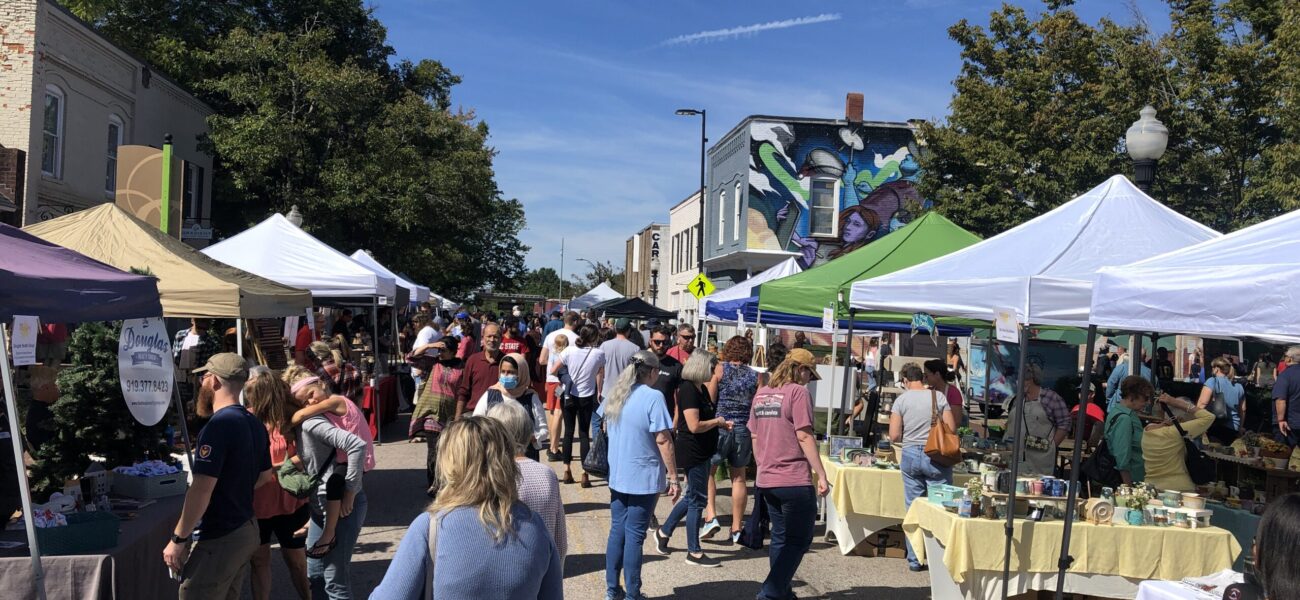 Picture of a street with tents set up with various venders and people walking and shopping